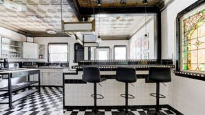 A kitchen with a checkered floor, black bar stools, and a large window with stained glass. - Oasis in Oklahoma City (Oklahoma City)