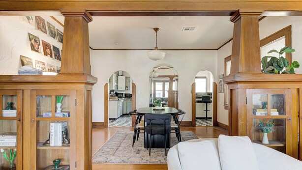 A spacious living area with a dining table, a sofa, and wooden cabinets with glass doors. - Oasis in Oklahoma City (Oklahoma City)