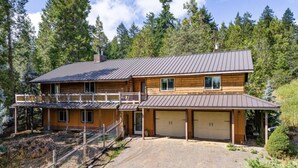 A two-story log cabin with a balcony, a garage, and a fenced driveway.