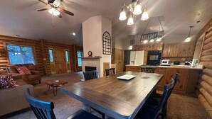 A log cabin interior with a dining area, kitchen, and living room.