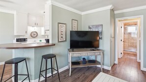 A modern kitchen with a bar area, a flat-screen TV, and two bar stools. - 1 Bed Beach Condo #131 1 Bedroom Condo by Sunset Shores Condominiums (Carpinteria)