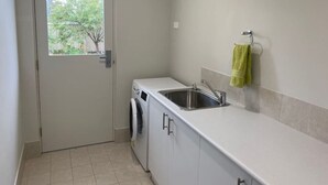 A compact laundry room with a washing machine, a sink, and a door with a window.