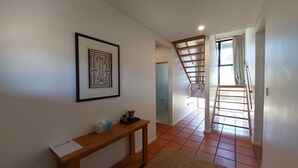 Un couloir avec une console en bois, un tableau encadré et un escalier menant à une autre pièce.