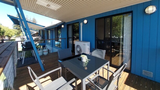Un espace extérieur abrité, équipé d’une table et de chaises, d’un barbecue et d’un ventilateur.