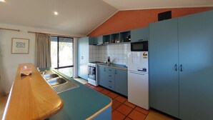 Une cuisine avec un long comptoir, une cuisinière, des placards et un réfrigérateur.