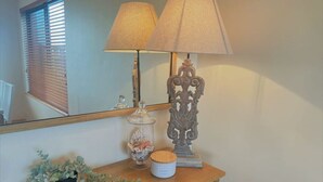 A wooden console table with a lamp, a decorative vase, and a small potted plant. - The Oceanaire, West Beach (West Beach)