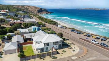 A coastal residential area with houses, a beach, and parked cars.