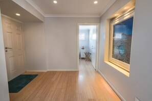 Un pasillo con piso de madera, una puerta a la izquierda y una ventana a la derecha.