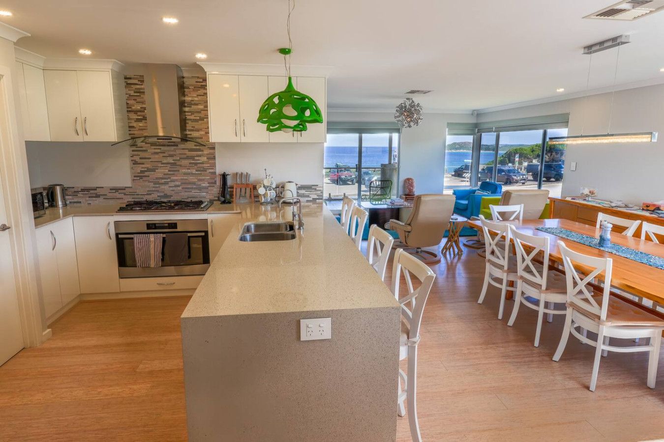 A modern kitchen with a central island, white cabinetry, and a stone backsplash.