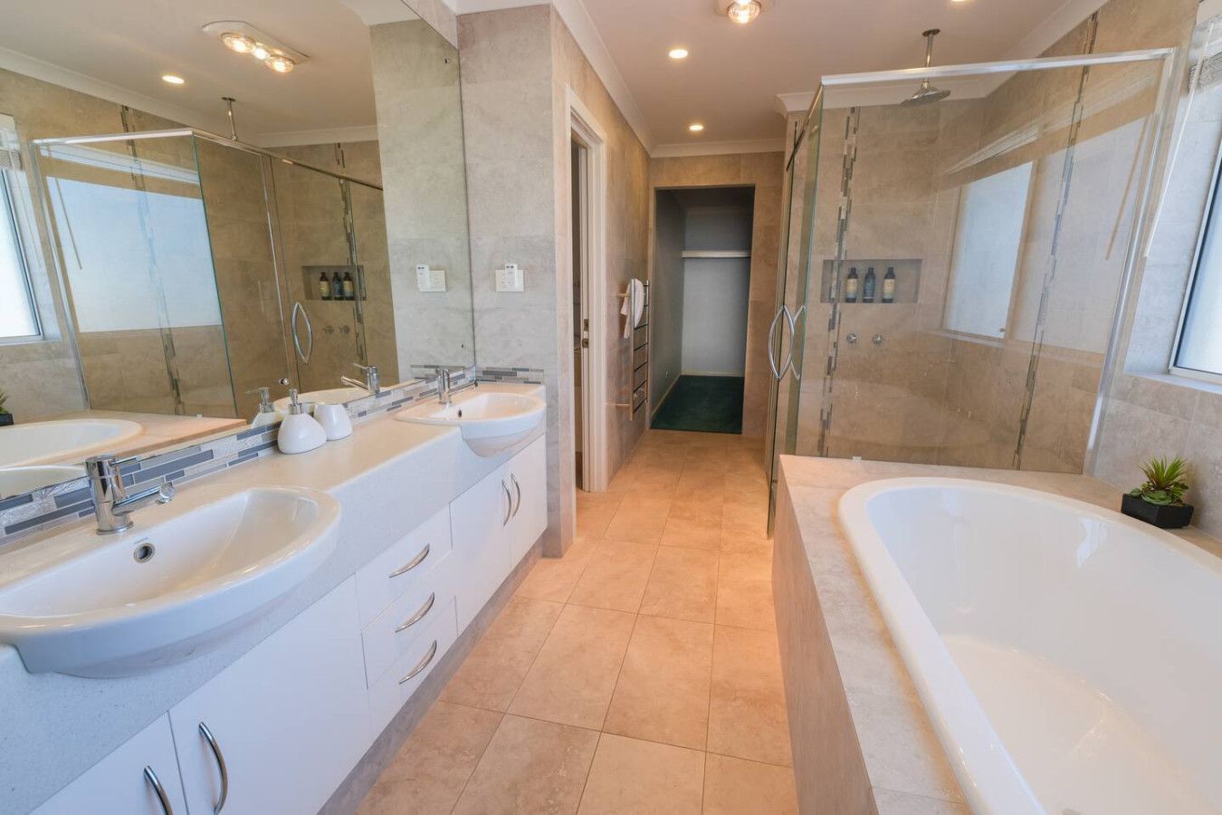 Un baño moderno con dos lavamanos, una bañera y cabina de ducha.