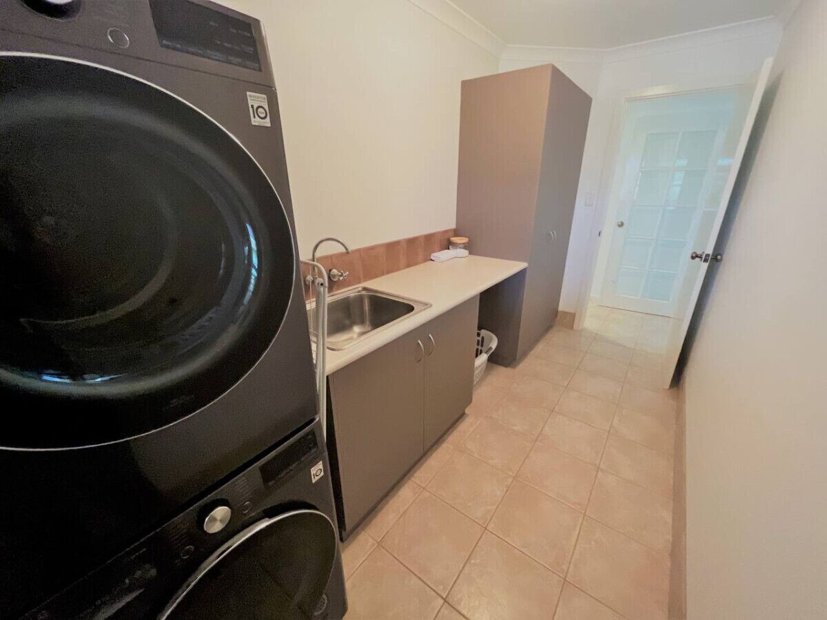 Une cuisine de taille réduite équipée d’un lave-linge, d’un évier et de placards.