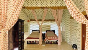 Una habitación con dos camas, un armario de madera y papel tapiz estampado.