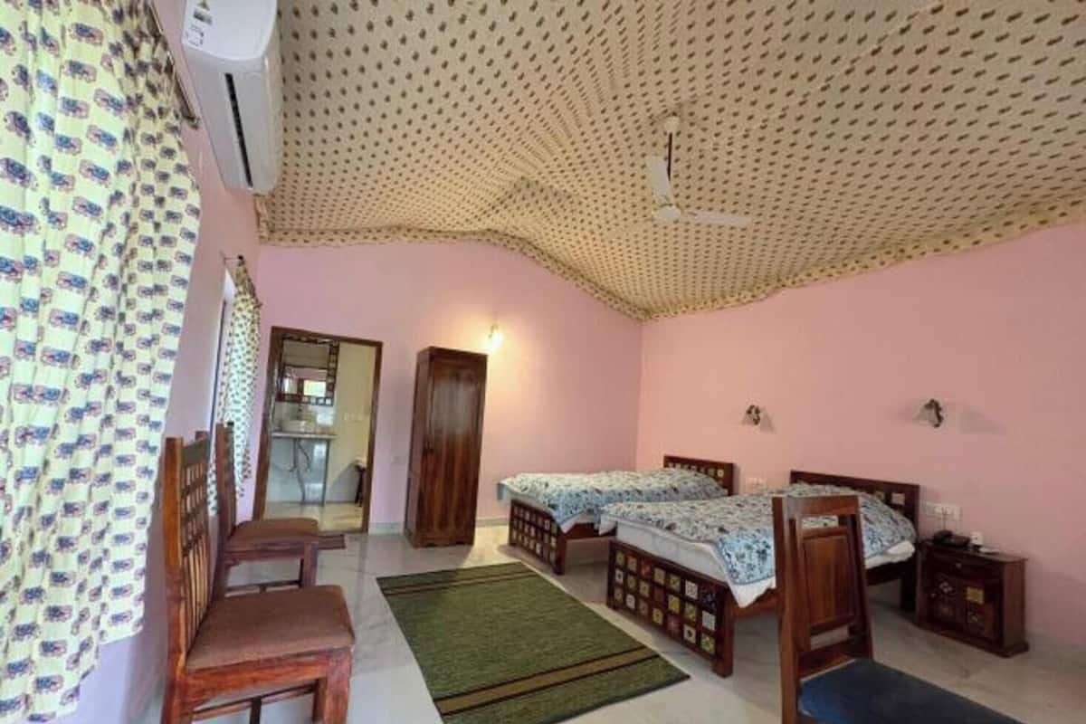 Un dormitorio con dos camas individuales, un banco de madera, un escritorio y una silla.