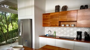 A modern kitchen with a stainless steel refrigerator, wooden cabinets, and a window overlooking greenery. - Beautiful Villa Lucia, Gated Tropical Retreat, Private Deck with Pool, Ojochal (Provincia de Puntarenas)