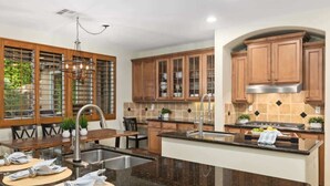 Una cocina moderna con armarios de madera, encimera de granito y comedor con mesa y sillas.