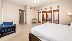 A bedroom with a large bed, a ceiling fan, a chair, and a view through a door. - Private Pool Home with Patio | La Quinta Cove (La Quinta)