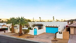 A residential house with a blue garage door, palm trees, and a clear sky. - Private Pool Home with Patio | La Quinta Cove (La Quinta)