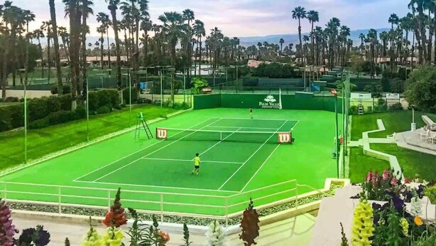Ein Tennisplatz, umgeben von Palmen und üppiger Vegetation.