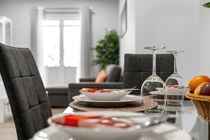Una mesa de comedor dispuesta con platos, vasos y una cesta de fruta.