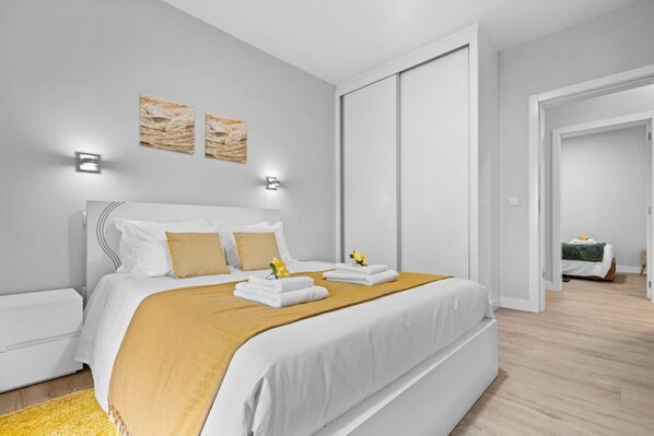 Habitación de hotel moderna con una cama grande, una mesita de noche y vistas a otra habitación.
