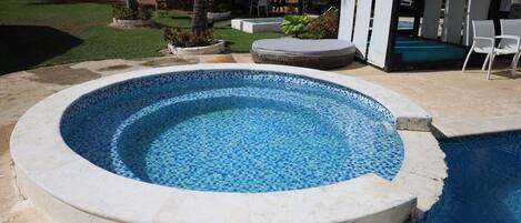 A circular pool with mosaic tiles, surrounded by a stone deck.
