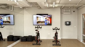 Un gimnàs amb cintes d'entrenament, un televisor a la paret i un mirall que reflecteix l'espai.