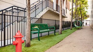 Un banc verd, un hidrant vermell i una estructura de joc infantil en un entorn urbà.