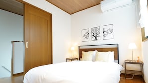 A hotel room with a large bed, wooden flooring, a wardrobe, and three wall-mounted tree-themed pictures. - KAMON/ 大阪万博まで30分/駐車場有り/大阪城まで徒歩圏内/空港からの送迎サービス有り(有料)/家族向け (Osaka shi Higashinari ku Nakamichi 2)