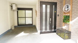 A hotel entrance with a glass door, a small outdoor seating area, and a neon sign. - KAMON/ 大阪万博まで30分/駐車場有り/大阪城まで徒歩圏内/空港からの送迎サービス有り(有料)/家族向け (Osaka shi Higashinari ku Nakamichi 2)