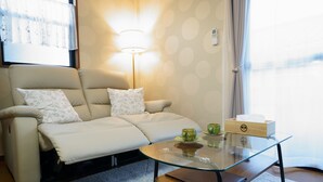 A modern living room with a sofa, a glass coffee table, and a lamp. - KAMON/ 大阪万博まで30分/駐車場有り/大阪城まで徒歩圏内/空港からの送迎サービス有り(有料)/家族向け (Osaka shi Higashinari ku Nakamichi 2)