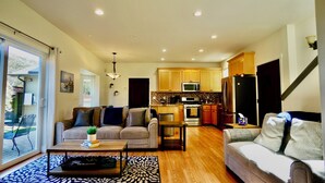 A spacious living room with a sofa, coffee table, and a view of the kitchen. - Fantastic 3 bedroom, 3 bath Coastal Home Close to the Beach and Restaurants (Moss Beach)