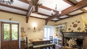 A cozy room with a wooden table, bench, and sofa, a fireplace, and a bookshelf filled with decorative items. - Allumiere by Interhome (Manziana/Canale Monterano)