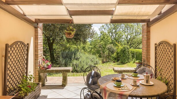A patio with a round table, chairs, and a hanging planter. - Allumiere by Interhome (Manziana/Canale Monterano)