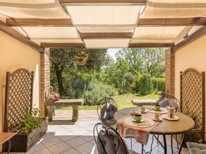 A patio with a round table, chairs, and a hanging planter. - Allumiere by Interhome (Manziana/Canale Monterano)