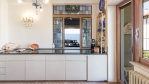 A kitchen with a central island, a chandelier, and a view through a glass door. - The Waves by Interhome (Santa Marinella)