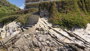 A stone staircase leading to a modern two-story building with balconies, surrounded by lush greenery and pink flowers. - The Waves by Interhome (Santa Marinella)