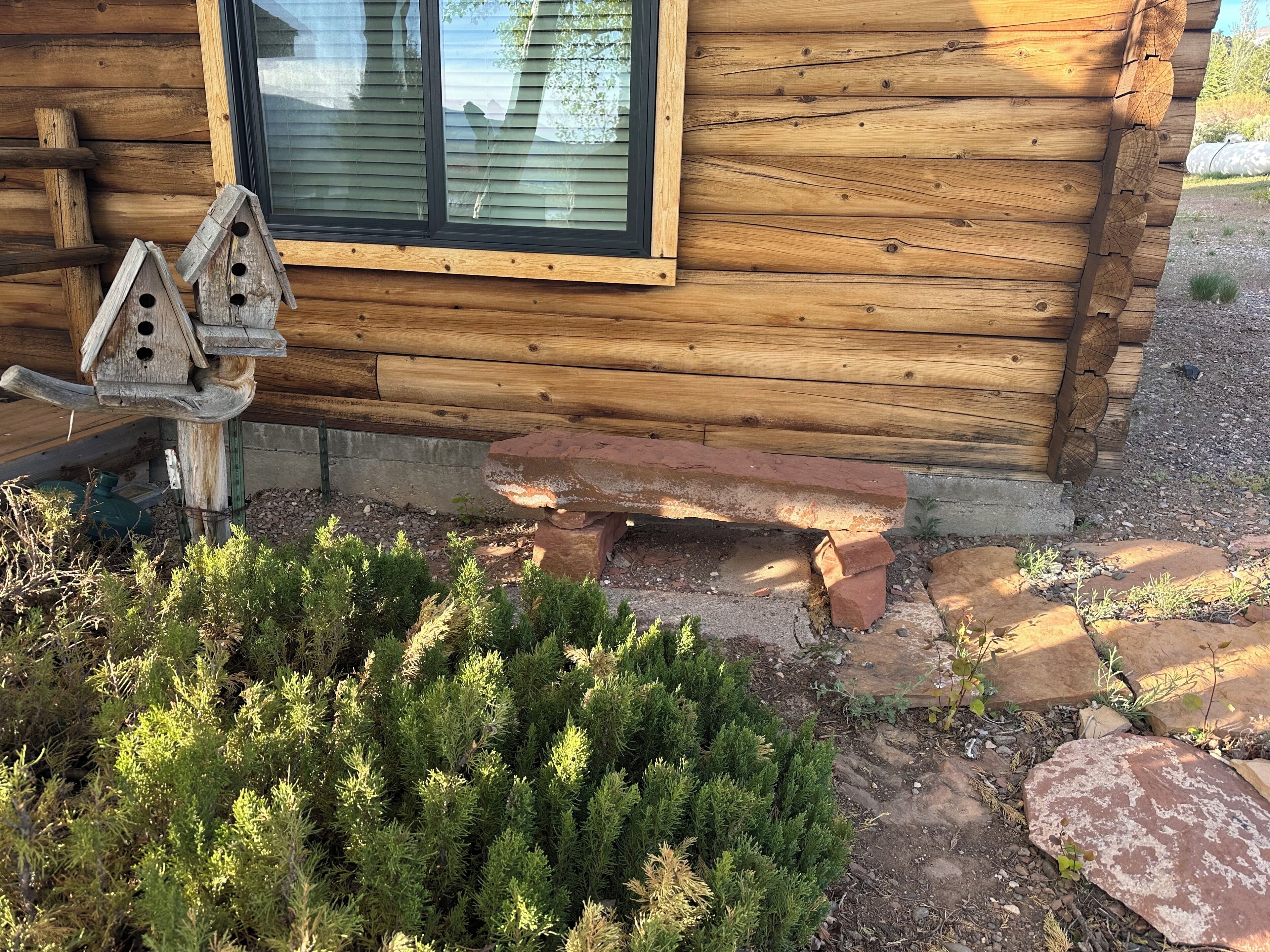 A wooden cabin with a window and a birdhouse in front.