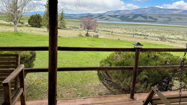 Una terraza de madera con vista a un campo cubierto de hierba y montañas.