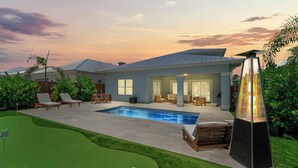 Une maison moderne dotée d’une piscine, d’un espace salon extérieur et d’un patio.