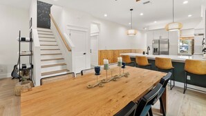 Une cuisine moderne dotée d’un îlot central en bois, d’une cuisinière intégrée et d’un coin repas avec une table et des chaises en bois.