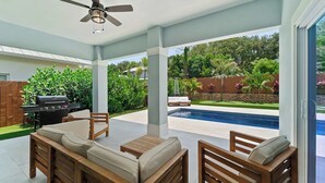 Un patio couvert avec une piscine, du mobilier d’extérieur et un barbecue.
