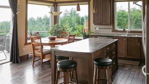 Una cocina amplia con una isla grande, taburetes de madera y vistas al exterior.