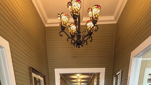 A hallway with wooden floors, a chandelier, and framed pictures on the walls. - Historic 1905 Victorian Home Near the  Rainbow River  & World Equestrian center (Dunnellon)