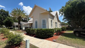 A single-story house with a gabled roof, a satellite dish, and a well-maintained front yard with a pathway leading to the entrance. - Historic 1905 Victorian Home Near the  Rainbow River  & World Equestrian center (Dunnellon)
