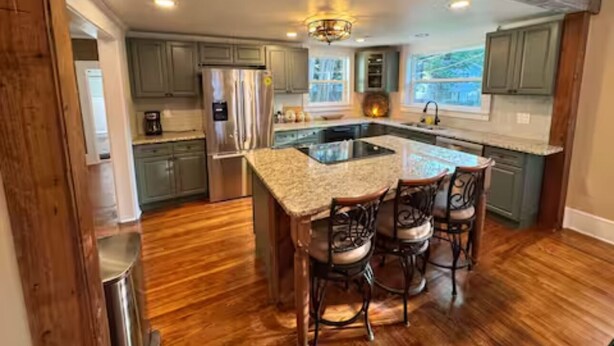 A kitchen with a central island, bar stools, and wooden flooring. - Historic 1905 Victorian Home Near the  Rainbow River  & World Equestrian center (Dunnellon)