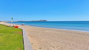 A beach with a clear sky, a flag, and a lifeguard stand. - BeachBumCondos (Puerto Penasco)