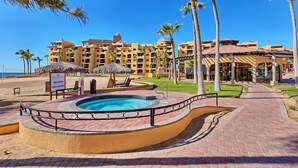 A resort with a swimming pool, palm trees, and a beach. - BeachBumCondos (Puerto Penasco)