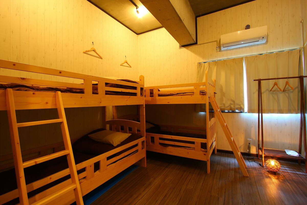 A room with bunk beds, a ladder, a hanging light fixture, and an air conditioning unit.