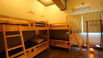 A room with bunk beds, a ladder, a hanging light fixture, and an air conditioning unit.