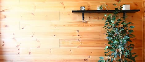 A wooden wall with a shelf holding a clock and a plant.